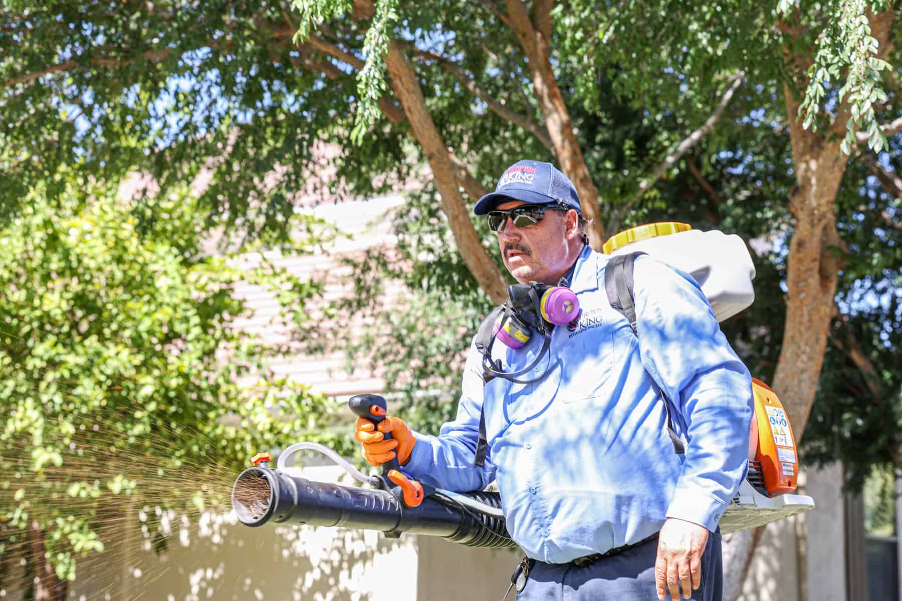 man spraying pest preventative granules around house
