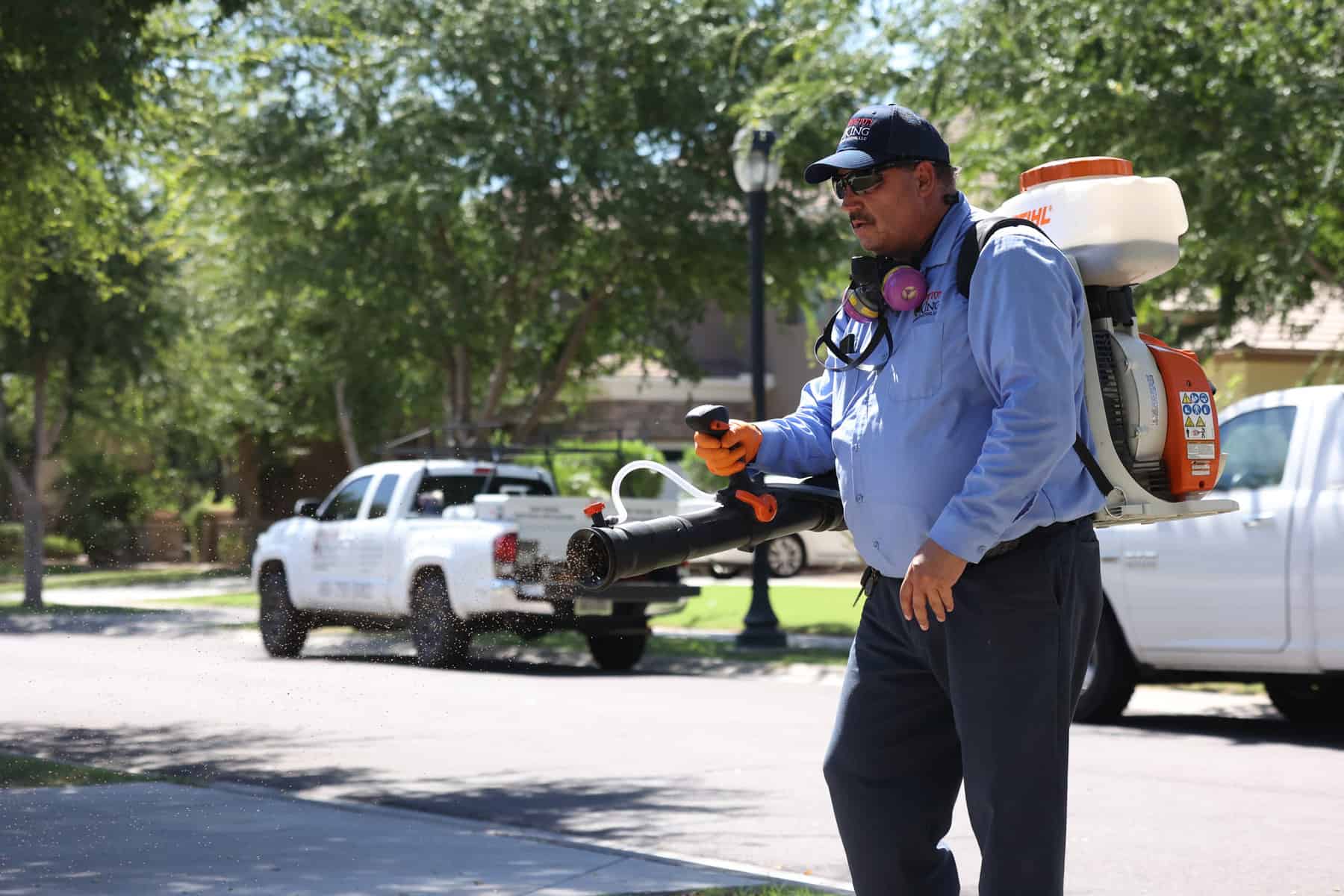 man spraying pest repellent granules in driveway